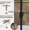 A diagram showing the features of a patio umbrella, including its crank mechanism and tilt function, against a plain background and a wooden fence. Podgląd zdjęcia produktu
