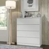 A white chest of drawers with books and decorative items on top, next to a floor lamp in a room with wood-paneled walls. Produktbild-Vorschau