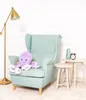 A purple plush octopus sits on a light blue armchair next to two small white tables. A gold floor lamp is on the left, and a small black alarm clock and a light blue vase are on the right table. Náhľad obrázku produktu