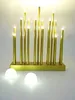 A decorative LED light fixture with multiple gold-colored candle-like lights on a gold base, with two small white LED lights in the foreground. Produktbild-Vorschau