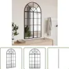 A black arched window mirror is mounted on a wall above a wooden dresser. A plant is on the left side of the dresser, and a scarf is hanging on the wall to the right of the mirror. Podgląd zdjęcia produktu