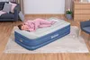 A woman sleeps on an inflatable air mattress in a room. Produktbild-Vorschau