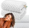 A woman is smiling and leaning on a stack of white blankets. Náhled obrázku produktu