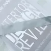 A close-up view of a transparent gray curtain with a satin ribbon trim, showing text printed on the fabric. Produktbild-Vorschau