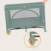 A green travel crib is shown with a close-up inset of a wheel with a lock mechanism. Náhľad obrázku produktu