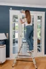 A woman is cleaning a glass door while standing on a ladder. Anteprima dell’immagine prodotto