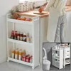 A person is preparing food in a kitchen, with a narrow storage shelf filled with food items next to them. An inset image shows the same shelf placed next to a toilet. Produktbild-Vorschau