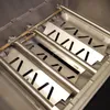 Close-up view of the interior of a grill, showing stainless steel heat deflectors and burner tubes. Produktbild-Vorschau