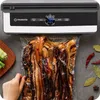 A vacuum sealer with a bag of food being sealed. Podgląd zdjęcia produktu
