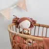 A stuffed doll and a stuffed monkey are sitting in a wicker crib, with a fabric banner in the background. Produktbild-Vorschau
