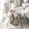 A plush blanket draped over a chair next to a bed. Produktbild-Vorschau
