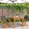 An outdoor patio scene with a wooden table and chairs set up under a large umbrella, surrounded by greenery and a wooden fence. Podgląd zdjęcia produktu