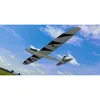 A remote-controlled glider airplane flying in a blue sky with clouds, with a green field and some buildings in the background. Produktbild-Vorschau