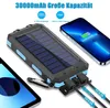 A solar power bank is shown charging a smartphone, with another device and cables in the foreground. Produktbild-Vorschau