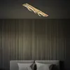 A modern wooden ceiling lamp with wavy LED lights is mounted on a dark ceiling above a bed with gray headboard and pillows. Produktbild-Vorschau
