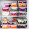 A refrigerator shelf filled with various sizes of clear plastic food storage containers filled with colorful fruits and vegetables. Produktbild-Vorschau