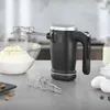 A black hand mixer is shown with baking ingredients including flour, butter, eggs, and blueberries on a kitchen counter. Produktbild-Vorschau