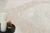 A close-up view of a rug with a decorative pattern, featuring two white candles and a diffuser on a black tray in the foreground. Produktbild-Vorschau