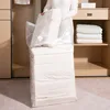 A person is holding a vacuum storage bag filled with white bedding in a closet. Produktbild-Vorschau