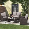 A patio set with a sofa, two chairs, and a coffee table on a patterned patio with grass in the foreground and a building with ivy in the background. Produktbild-Vorschau