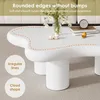 A white, cloud-shaped coffee table with decorative elements on top, set in a living room environment. Voir les images du produit