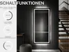 A vertical illuminated mirror is shown in a modern interior setting, with text overlays explaining its functions. Produktbild-Vorschau