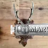 A tube of Marvis Whitening Mint toothpaste is displayed horizontally in front of a mounted set of deer antlers against a wooden background. Anteprima dell’immagine prodotto
