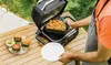 A person is using a grill outdoors to cook food, with burgers and fries visible. Anteprima dell’immagine prodotto
