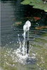 A solar-powered fountain pump is operating in a pond with koi fish swimming in the background and lily pads on the surface. Produktbild-Vorschau