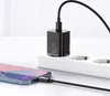 A black 20W USB-C charger is plugged into a white power strip, with a smartphone connected to it via a black cable. Produktbild-Vorschau