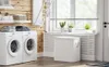 A laundry room with a washing machine, dryer, laundry basket, and plants. Produktbild-Vorschau