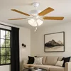A white ceiling fan with wooden blades and integrated lights is mounted on a white ceiling above a sectional sofa. Anteprima dell’immagine prodotto