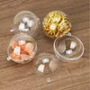 Several clear plastic spheres are arranged on a wooden surface. Some spheres are filled with orange-colored rocks, some with gold shredded paper, and others are empty. Produktbild-Vorschau