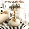 A small round side table with a decorative base and a tray top, placed next to a sofa and on a rug. Produktbild-Vorschau