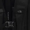 A close-up view of a black backpack strap with a buckle and the North Face logo. Voir les images du produit