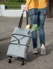 A person is walking with a grey shopping trolley bag filled with groceries. Náhľad obrázku produktu