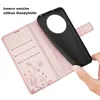 A hand is holding a black phone case over an open rose gold wallet case with floral embossing. Produktbild-Vorschau