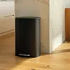 A black pedal trash can is placed on a wooden floor next to a marble wall in a kitchen. Podgląd zdjęcia produktu