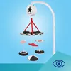 A baby mobile with a music box attached to a crib arm, against a blue background. Produktbild-Vorschau