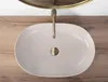 A top-down view of a beige matte washbasin with a gold faucet and drain, set on a wooden countertop. Podgląd zdjęcia produktu