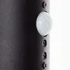 A close-up view of a black outdoor wall lamp, showing the motion sensor and mounting screws. Produktbild-Vorschau