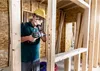 A construction worker is drilling holes in a wooden frame. Produktbild-Vorschau