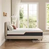 A mattress on a bed frame in a bedroom with large windows overlooking greenery. Produktbild-Vorschau