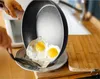 A person is cooking eggs in a frying pan over a plate. Voir les images du produit