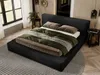 A bedroom scene with a black upholstered bed as the main focus, styled with bedding and decorative elements. Náhľad obrázku produktu