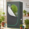 A grow tent is set up indoors next to a window with plants on the windowsill. The tent is partially open, revealing plants inside. Other potted plants are visible around the tent. Náhled obrázku produktu