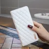 A hand holding a white quilted phone case. Produktbild-Vorschau