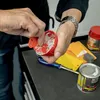 A person's hands are shown working with a small red container filled with white material, possibly putty or filler, with other tools and containers visible in the background on a dark surface. Anteprima dell’immagine prodotto