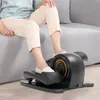 A person is using a compact elliptical machine while sitting on a couch. Podgląd zdjęcia produktu