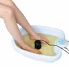 A person's legs and feet are submerged in a white foot bath filled with yellow water. A black device is in the water, and a white control panel is attached to the side of the tub. Produktbild-Vorschau